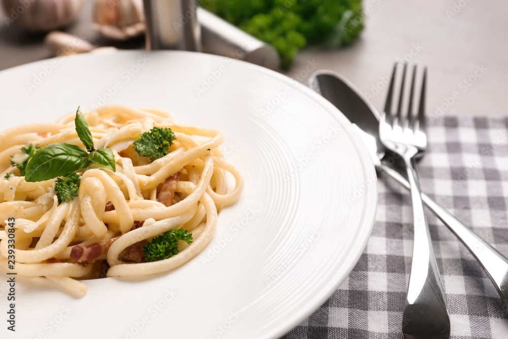 Plate with delicious pasta carbonara on grey table, closeup