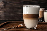 Glass of tasty aromatic latte on wooden board