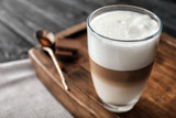Glass of tasty aromatic latte on wooden board