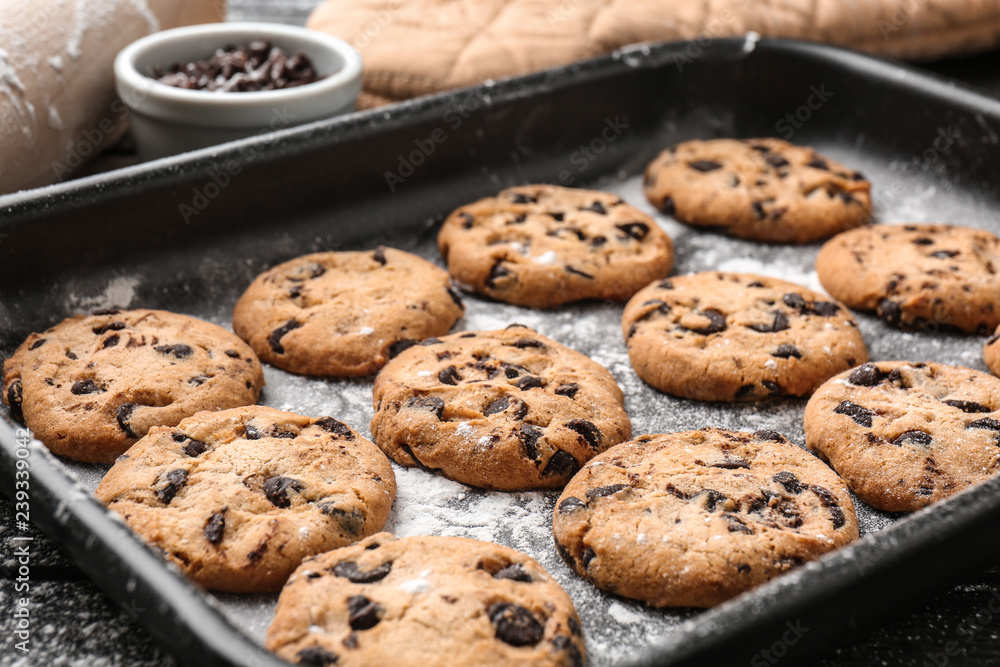 Tasty cookies with chocolate chips on baking tray - obrazy, fototapety, plakaty 
