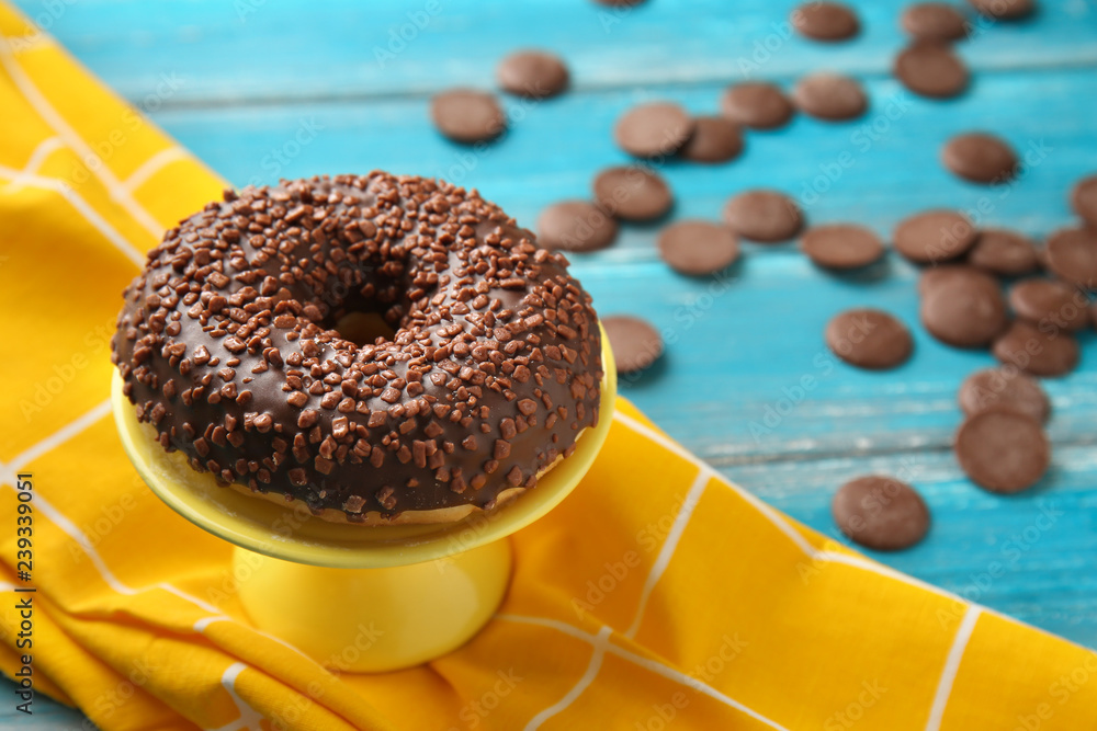 Delicious glazed doughnut with chocolate chips on color wooden table
