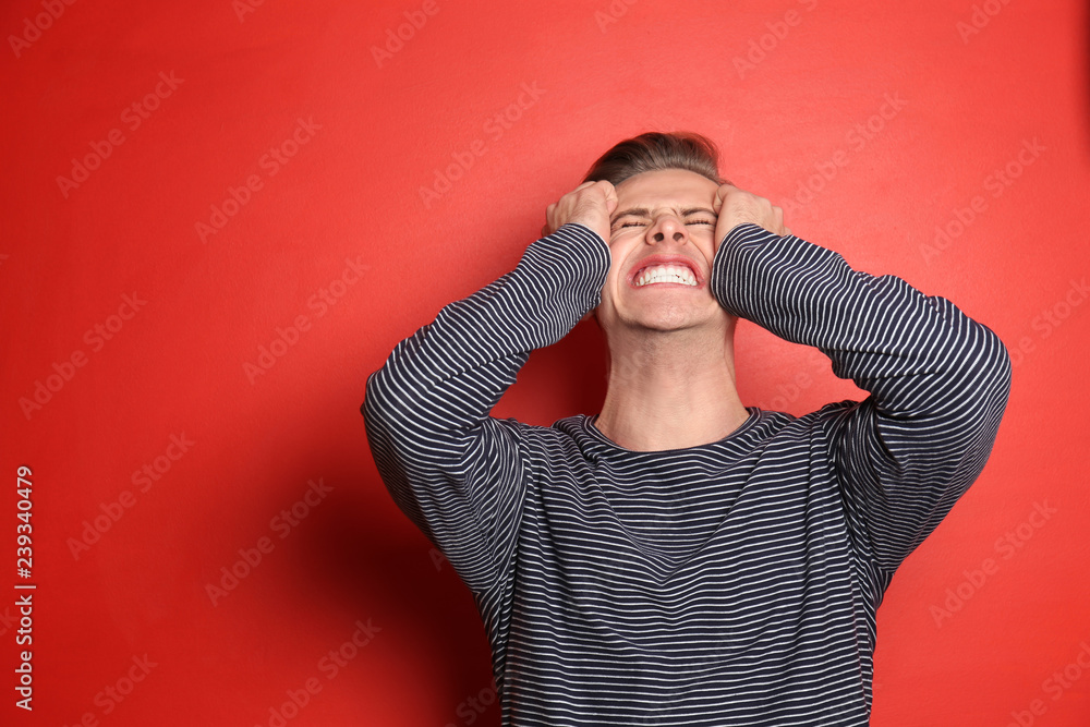 Portrait of stressed young man on color background