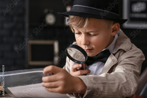 Fotografía Cute little detective working with evidence at table