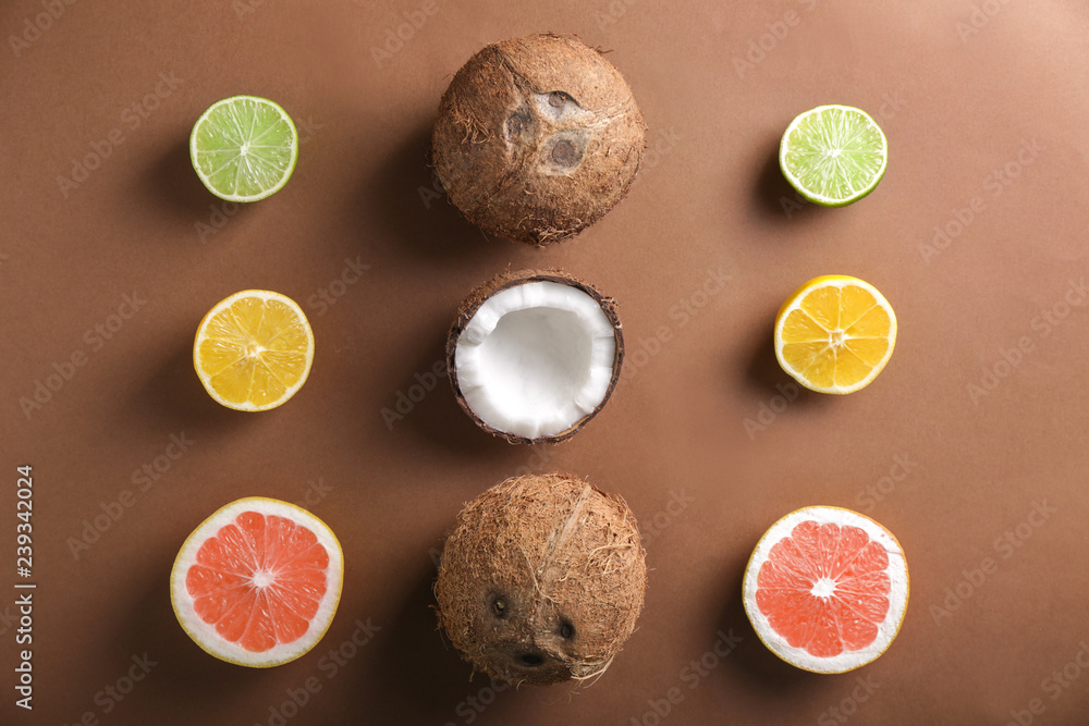 Ripe coconuts and citrus fruits on color background