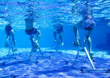 Touristen doing aqua aerobics on exercise bikes in swimming pool tropical hotel