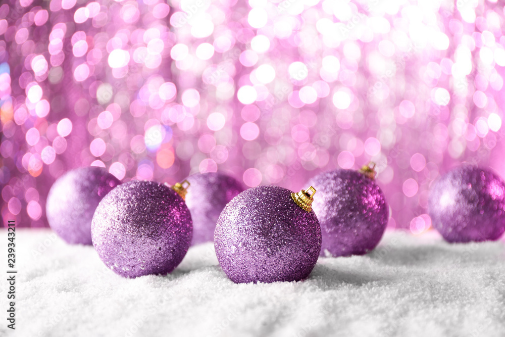 Christmas baubles on snow against blurred lights