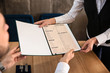 © Pixel-Shot - Young waitress showing man a menu in restaurant