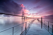 © Robert - Sunrise colors the clouds reflected in Tagus River and frame the Vasco da Gama bridge in Lisbon Portugal Europe