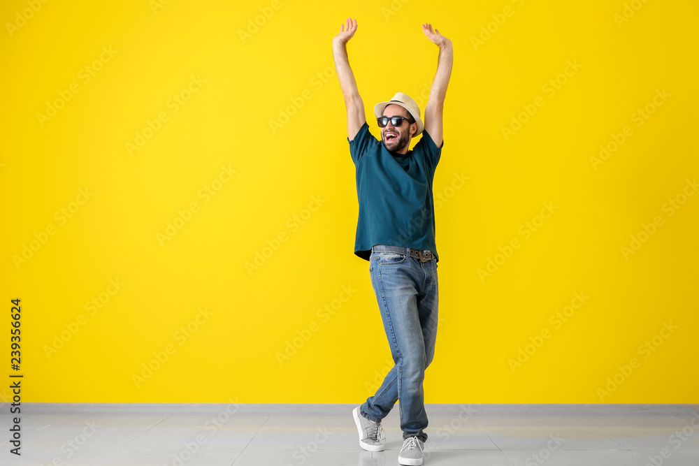 Handsome young man dancing near color wall