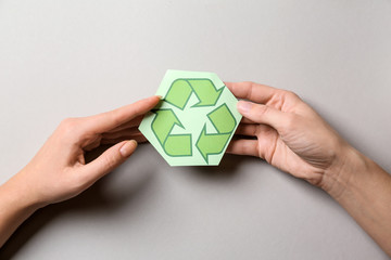 Female hands with recycling symbol on light background