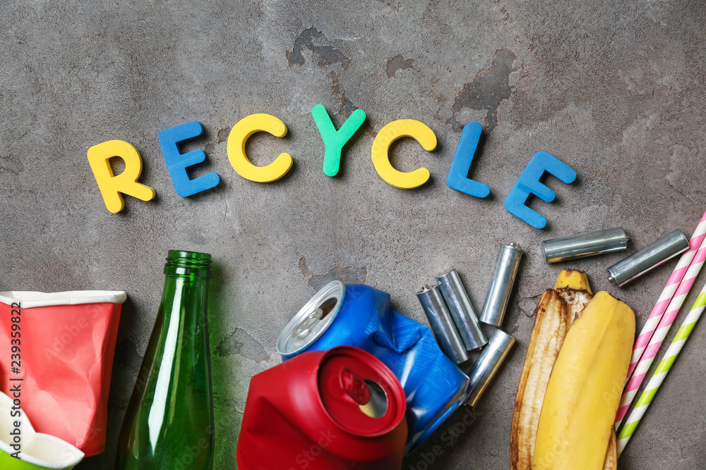 Word RECYCLE and different garbage on grey background