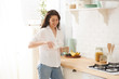 © Elena Kharichkina - Young happy woman drinking coffee on the kitchen in the morning.