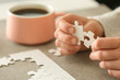 © Pixel-Shot - Woman assembling puzzle on table, closeup