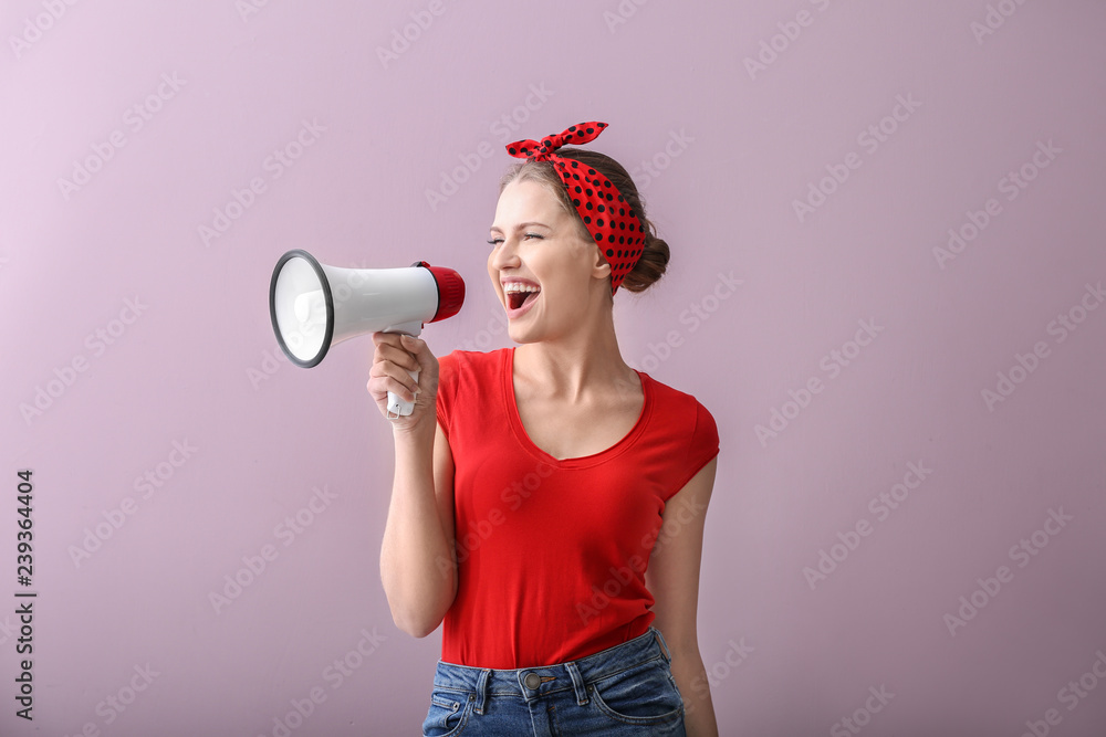 Young woman with megaphone on color background
