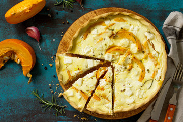 Classic Quiche Lorraine Pie with Pumpkin and Feta Cheese on blue concrete or stone table. Top view flat lay background.