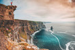 The Cliffs of Moher in Ireland. Woman standing at the top over the sea landscape