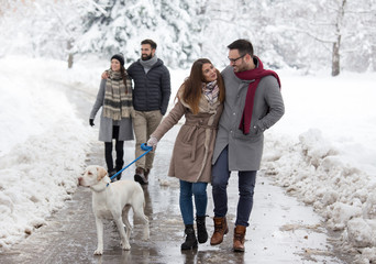 Couple walking dog in park on snow