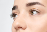 Fototapeta Panele - Young woman with beautiful eyelashes on light background, closeup view