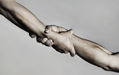 Rescue, helping gesture or hands. Strong hold. Two hands, helping hand of a friend. Handshake, arms, friendship. Friendly handshake, friends greeting, teamwork, friendship. Close-up. Black and white