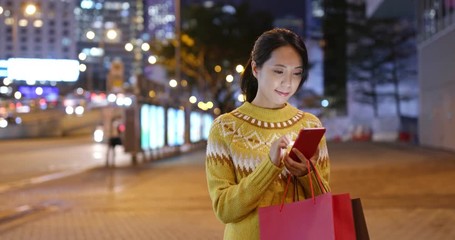 Poster - Woman holding with shopping bag and use of mobile phone in city at night