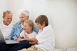 © Erickson Stock - Multi-generational family sitting on the floor looking at a laptop.