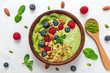 matcha green tea smoothie bowl with fresh fruits, berries, nuts, seeds and granola with a spoon for healthy breakfast