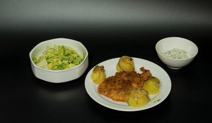 Fried wiener chicken fillet with potatoes and fried onion and two salads