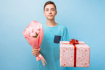 Teen boy gives a gift and flowers, a man in love, on a blue background