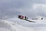 Fototapeta Natura - People move up on moving carpets with snow tube at ski resort