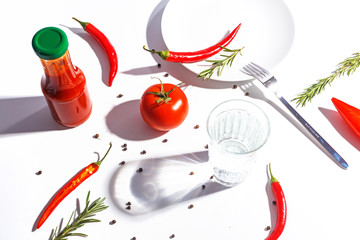 Red hot peppers, tomatoes, rosemary and spices on white background. Table setting. Top view.