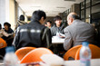 © Erickson Stock - Teenage boy sitting in a cafeteria with friends and a senior male teacher.