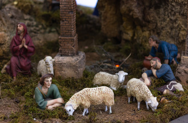 Nativity set with shepherds resting and sheep eating grass. Christian religion, Christmas holiday season decoration scene concepts