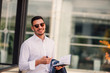 © qunica.com - An eloquent businessman is outside, he is enjoying in the beautiful weather while looking at the notebook. Urban businessman on the move.