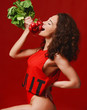 Pretty cheerful young sport woman hold fresh radish with green leaves and pointing finger. Dieting