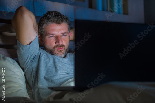 Face Expression - man alone in bed playing cybersex using laptop computer ...