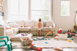 A little boy playing in a messy living room. 
