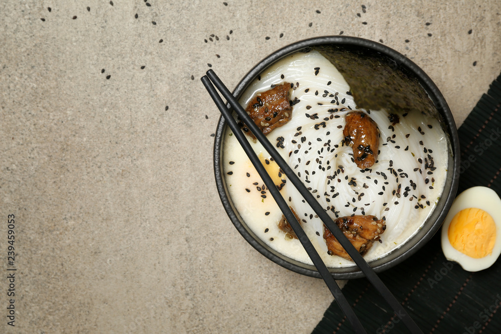 Tasty Chinese soup in bowl on grey table