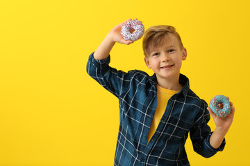 Canvas Print - Cute little boy with donuts on color background