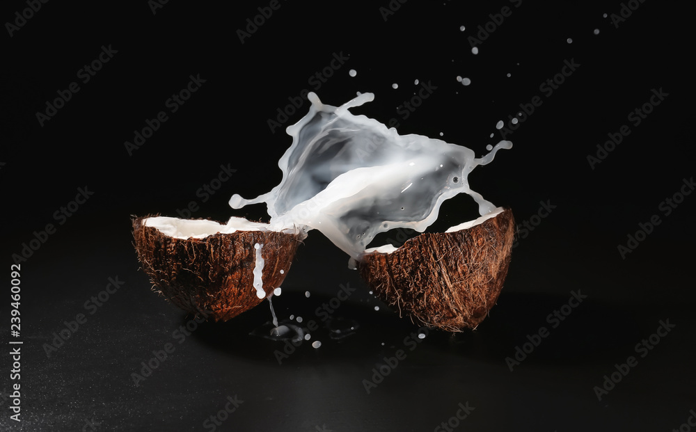 Ripe coconut and splash of milk on dark background