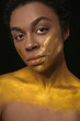 © Pixel-Shot - African-American woman with golden paint on her body against black background