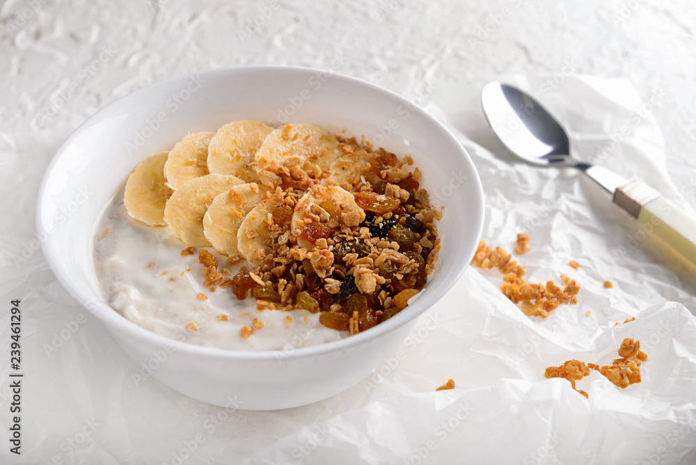 Bowl with tasty granola and yogurt on white table