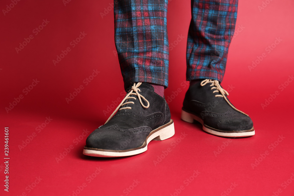 Young man in stylish shoes on color background, closeup