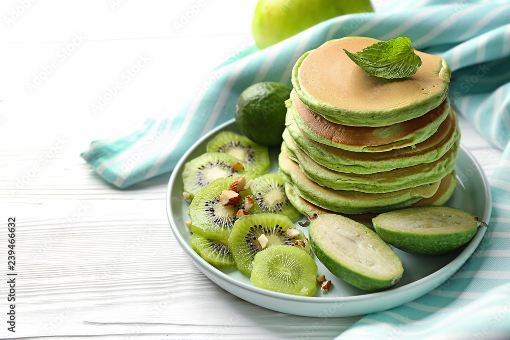 Tasty green pancakes on white wooden table