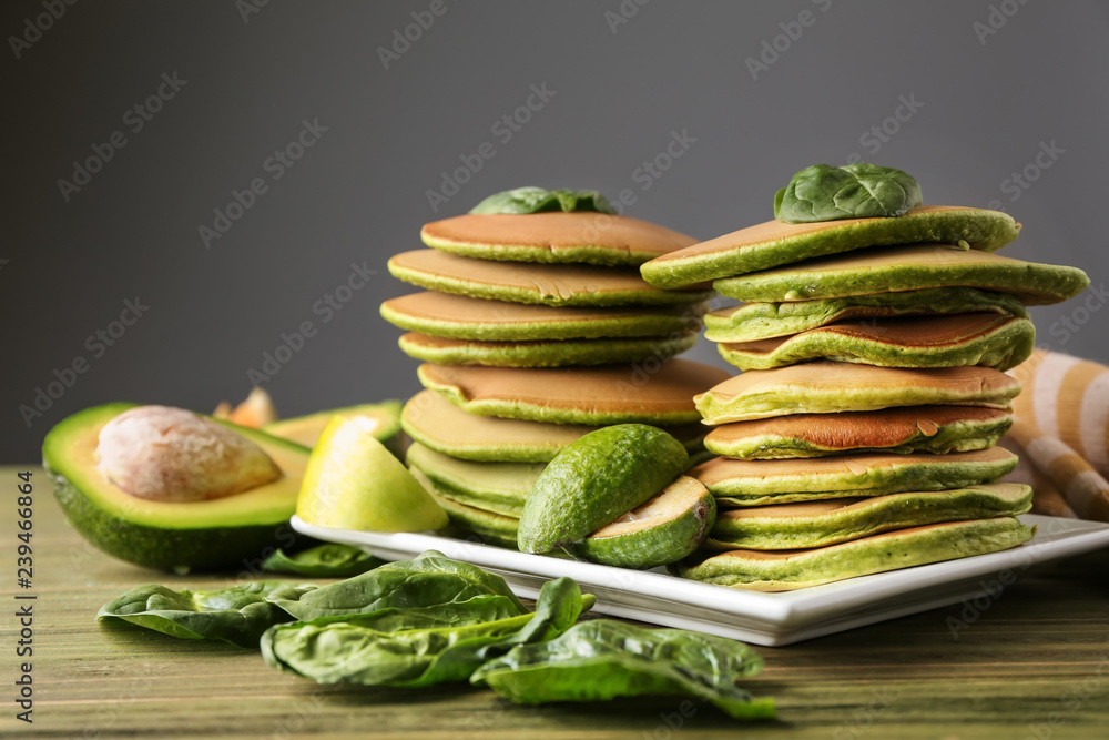 Tasty green pancakes on wooden table