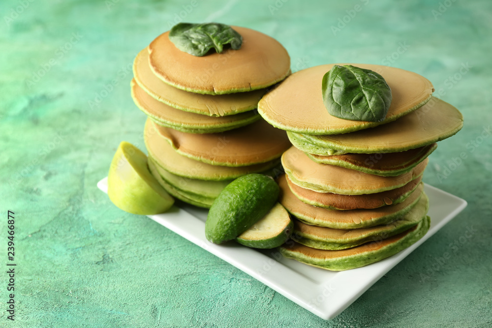 Tasty green pancakes on color table