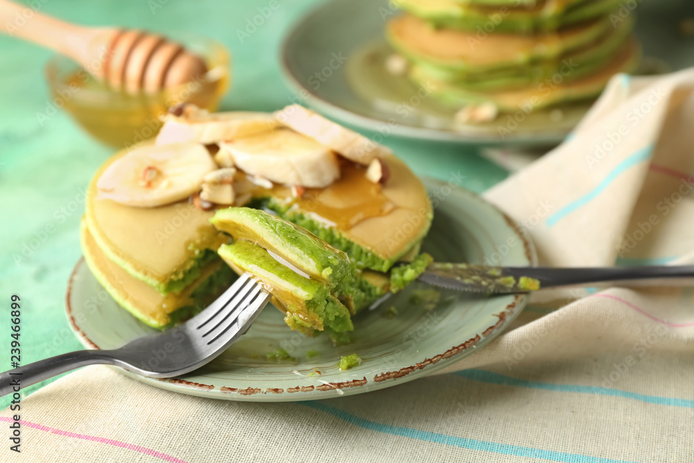 Plate with tasty sweet green pancakes on color table