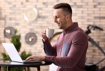 Sticker - Young man drinking coffee while working with laptop at home