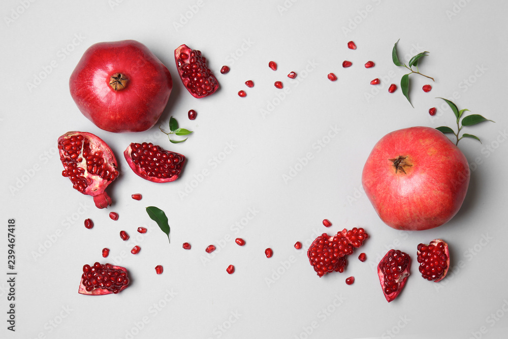Frame made of ripe pomegranates and seeds on light background