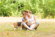 © oksix - Adorable couple daughter and mom sitting on a grass with their pets