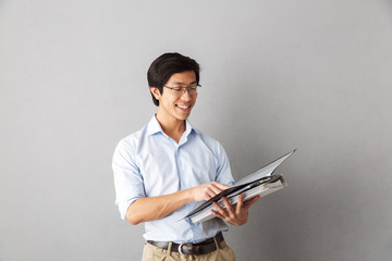 Wall Mural - Happy asian man standing isolated over gray